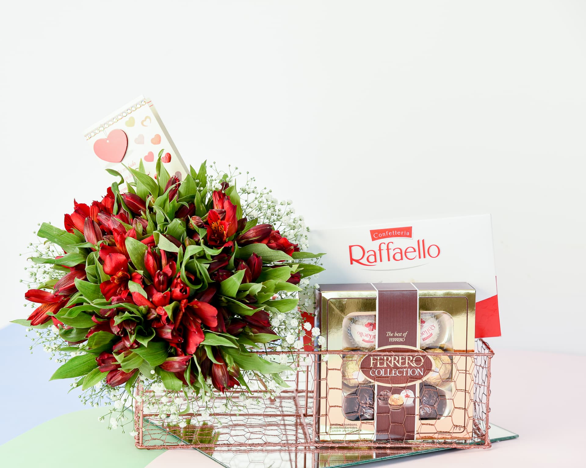 Cesta aramada rose gold com astromelias vermelhas e chocolates