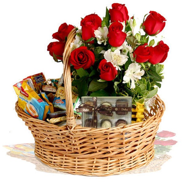 Cesta de vime com rosas vermelhas, bombons e biscoitos